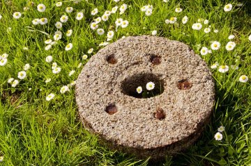 mlýnský kámen ležící na trávníku
