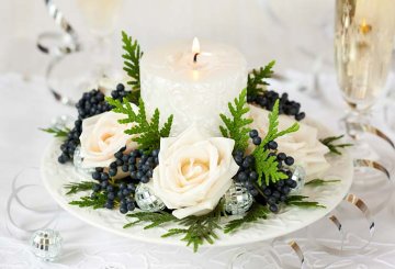 vánoční dekorace z růží, svíčky, zeravu a černých bobulí