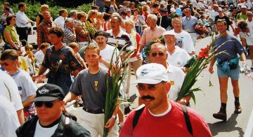 účastníci pochodu vcházejí do Nijmegen po Via gladiola s kyticemi mečíků, foto Wikipedia, Vincent de Groot